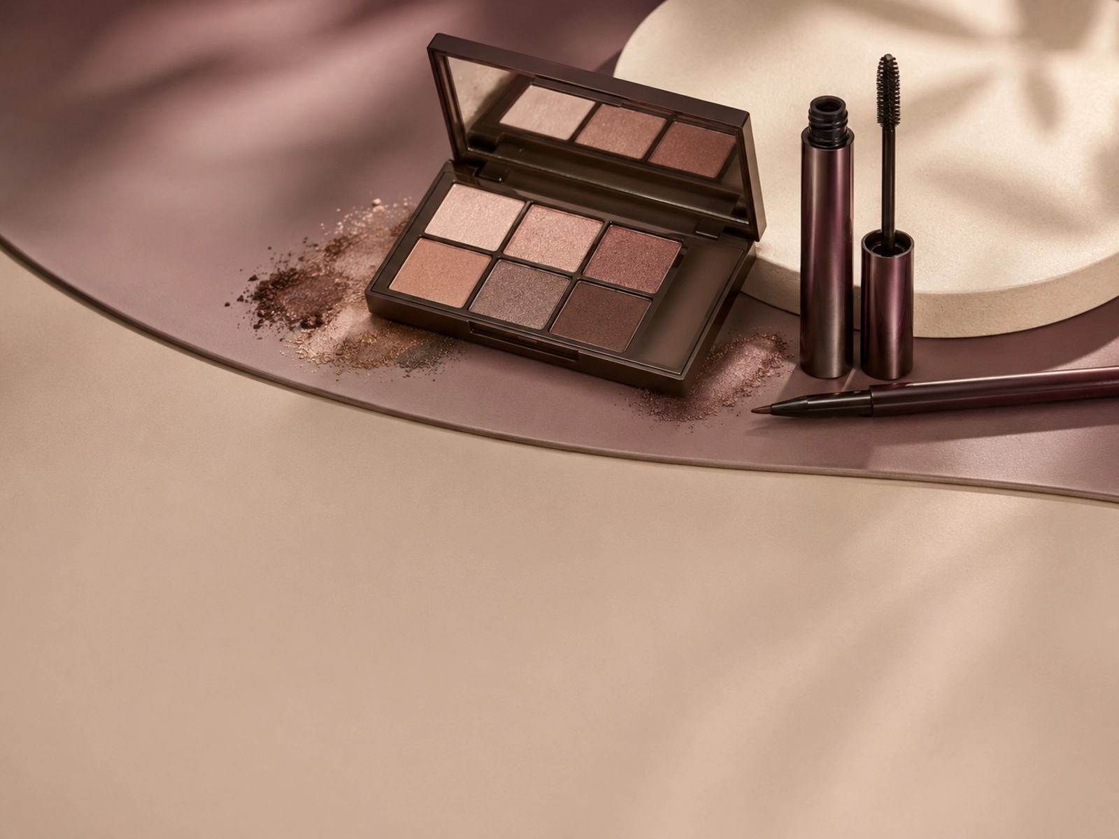 Makeup brushes and neutral eye products arranged in a restrained editorial composition.